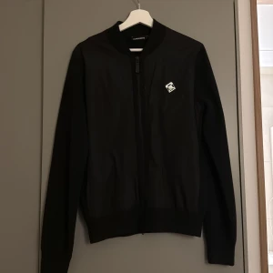 Svart cardigan från J.Lindeberg - Svart cardigan från J.Lindeberg. Använd fåtal gånger, bra skick.