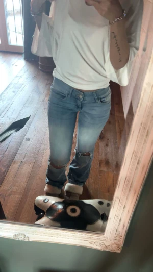 Ljusblå bootcut jeans med slitningar - Säljer ett par ljusblå jeans med bootcut-modell och slitna knän ifårn Nelly. Dem är lågmidjade och Jeansen är uppsydda i längden. 