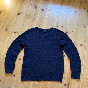 Mörkblå stickad tröja Polo Ralph Lauren - Kabelstickad mörkblå tröja från Polo Ralph Lauren i storlek XL men sitter som M/S.använd fåtal gånger och e ganska bra skick,ända defekten är att kragen kan vara lite stor men inget för extremt,köpte denna på Plick och nypris runt 2000, hör av er vid frågor å funderingar✌️