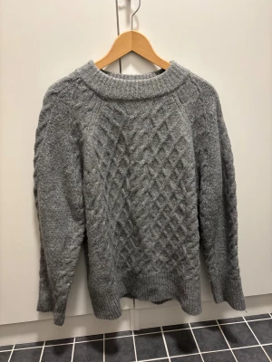 Stickad tröja grå - Grå stickad tröja med klassiskt kabelmönster.