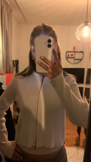 Vit ribbad kofta från Brandy Melville - Säljer en vit ribbad kofta från Brandy Melville med dragkedja framtill. Koftan har långärmad passform och är tillverkad i  stickat material. Den e använd förtal gånger, så i ett väldigt bra skick. 