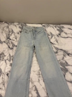 Ljusblå raka jeans från 157 - Ljusblå jeans från 157 med klassisk femficksdesign och vida ben. Jeansen har hög midja och är tillverkade i denim av bomull. Dragkedja och knapp framtill, samt bälteshällor. Finns små fläckar men det är ingenting man tänker på. Säljes pga ej min storlek. 