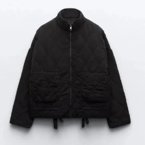 Höst jacka  - Quiltad svart jacka med hög krage, två stora fickor framtill och dragkedja hela vägen. Jackan har en loose passform och är perfekt för lager-på-lager. Snyggt mönstrad yta och justerbar nederkant med snörning.