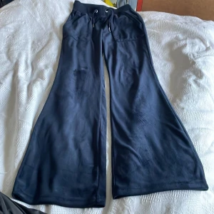 Mörkblå wide mjukisbyxor Bondelid XS - Snygga mörkblå mjukisbyxor från Bondelid i storlek XS. Byxorna har breda ben, ribbad midja med snörning och praktiska fickor. Materialet är mjukt och skönt, perfekt för chill dagar. Stilsäker och avslappnad look med wide fit.Juicy liknande byxor.