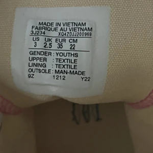 Rosa höga sneakers med snörning - Säljer ett par snygga höga sneakers i ljusrosa textil med vita snören och gummisula. Klassisk design med rund tå och metallöglor. Perfekt för dig som vill sticka ut med färg på fötterna. Storlek 35.