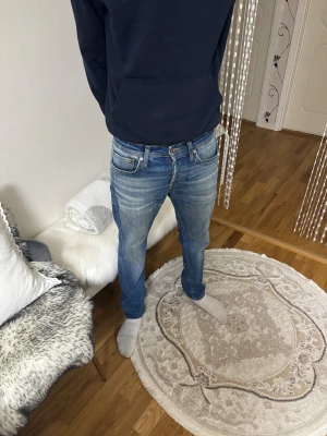 Blå jeans från Jack & Jones Comfort Mike - Säljer ett par snygga blå jeans från Jack & Jones, modell Comfort Mike. Jeansen har klassisk femficksdesign, raka ben och orangea kontrastsömmar. Materialet är slitstarkt denim med  tvättade detaljer och knappgylf. Perfekt för dig som gillar avslappnad stil.