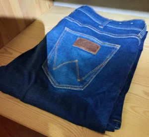 Wrangler Greensboro jeans blå  - Snygga Wrangler Greensboro jeans i klassisk blå färg med kontrastsömmar och ikonisk bakficka med läderpatch. Modellen har rak passform och normal midja, tillverkade i slitstarkt bomullsjeansmaterial. Perfekta för dig som gillar tidlös denimstil.