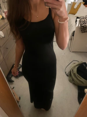 Svart långklänning med smala axelband - En svart tajt långklänning köpt här på plick. Säljer för att den är lite för kort för mig (jag gillar att ha ner till fötterna). Storlek 12-13 men skulle säga att den sitter som en xs. Sömmen har gått upp jätte lite där fram men inget man tänker på och väldigt lätt att sy.