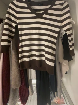 Randig brun och vit tröja H&M - Säljer en brun och vit randig tröja från H&M i storlek S. Tröjan har v-ringning, trekvartsärm och är i mjukt, stretchigt material. Perfekt för dig som gillar klassiska ränder och vill ha en enkel men snygg look.