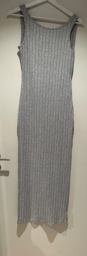 Grå ribbad långklänning från SHEIN - Säljer en grå långklänning från SHEIN i storlek S. Klänningen är ärmlös med rundad hals och har ett ribbat mönster som ger en snygg struktur. Materialet är mjukt och stretchigt, perfekt för en chill och stilren look.