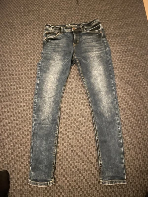 Blå skinny jeans från LAB Industries - Säljer ett par blå skinny jeans från LAB Industries i storlek 164. Jeansen har en snygg tvättad look med ljusare partier och klassiska fickor både fram och bak. Perfekta för dig som gillar en tight passform och stilren denim.