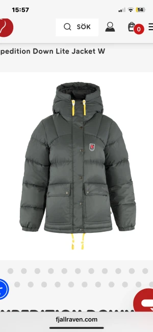 Mörkgrå Fjällräven pufferjacka - Säljer en mörkgrå pufferjacka från Fjällräven med gul snörning och huva. Jackan har två stora fickor med knappar, dragkedja och Fjällräven-logga på bröstet. Perfekt för kalla dagar och har en riktigt schysst streetstil.