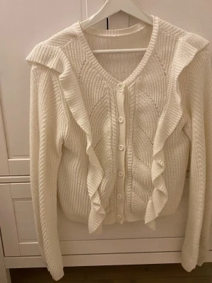 Vit stickad kofta med volanger! - Så söt vit kofta utan lapp. Älskar denna men kommer tyvärr inte till användning. Använd knappt 3 gånger. Storlek 146/152 men mer som en Xs.Pris kan diskuteras💕