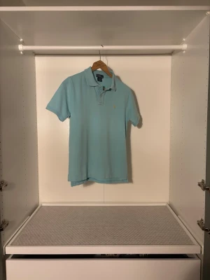 Polo Ralph Lauren Slim Fit Cltton Mesh Polo Shirt | Ljusblå | För Kille | - Säljer en piké från Ralph Lauren i ljusblå/turkos färg. Fantastiskt kvalité, inga missfärgningar eller märken på ärmar eller krage.   Storlek: L Bröst: 41 cm Längd: 62 cm  Leverans sker senast dagen efter :)