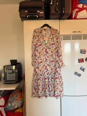 Odd Molly blommig långklänning XS - Superfin långklänning från Odd Molly i modellen Harley Dress, färg Mauve Chalk. Klänningen har ett blommigt mönster i lila, rosa, orange, grön och beige på ljus botten. Långärmad med v-ringad hals och volangdetaljer nedtill. Tillverkad i ett mjukt och luftigt material. Från märket Odd Molly. Storlek 0 som enligt deras storleksguide motsvarar en XS, men passar mer en S. kanske en liten M.  Helt ny med tags/ prislapp fortfarande kvar. 