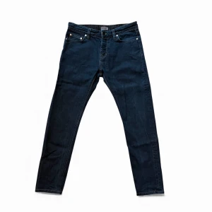 Mörkblå Filippa K jeans, storlek 31/32, bra skick - Mörkblå Filippa K jeans i modellen M. Stan Raw Stretch. Stilrena och tidlösa jeans med stretch för bekväm passform och snygg siluett. Jeansen är använda en del men fortfarande i bra skick, med normalt slitage. Modellen kan upplevas som något liten i storleken, så se måtten/storleken noga. Storlek 31/32. Skicka gärna ett meddelande om du vill ha fler bilder eller har frågor!