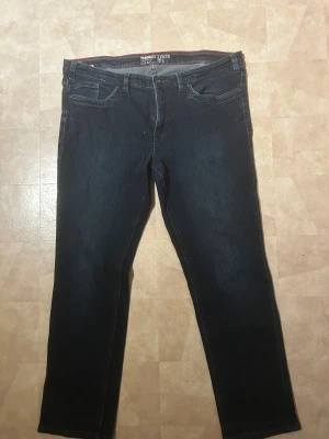 Mörkblå Paddock's Ranger Pipe jeans - Snygga mörkblå jeans från Paddock's Ranger Pipe med tight leg och låg midja. Klassisk femficksmodell med kontrastsömmar i rött och detaljerad bakficka. Perfekt för dig som gillar en smalare passform och stilren look.