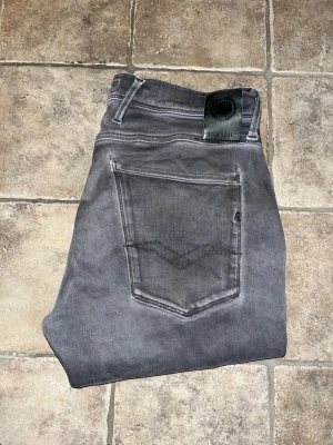 Replay jeans - Snygga gråa jeans från Replay. Jeansen är bekväma och sköna och har en tvättad look. Midja 39cm, längd 103cm. Obs jeansens matrial har blivit noppriga på knäna - se bild 6. JAG SKICKAR EJ FLER BILDER NÄR JAG BÄR JEANSEN! för storleksguide hänvisar jag till måtten och för bättre inblick i passformen rekommenderar jag att googla på modellnamnet. kolla måtten noggrant :) !!