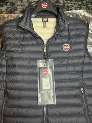 Marinblå Colmar Väst - Tja! Säljer nu denna riktigt schyssta Colmar Västen i färgen ”Navy Ice”. Påse, Klädhängare och Lappar ingår! Västen är i princip i nyskick, endast använd fåtal gånger. Storlek 52, sitter som M/L, Passar 180-195! Autentisk med QR-Scan i för att verifiera! Hör av dig vid minsta fråga eller fundering!🌟