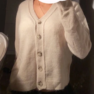 Fluffig beige cardigan med knappar - Säljer en super söt fluffig beige cardigan med knappar ifrån Zara! Är i strl XL men ska vara mindre men ville ha så den ungefär är som en strl S i vanliga fall, super mysig och gullig topp perfekt till våren! 💕 Säljer för 100kr!