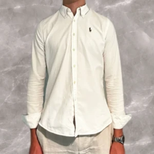 Ralph Lauren Skjorta - Säljer min vita ralph lauren skjorta som nu blivit för liten☺️ Skjortan är i 9/10 skick och har strl 6 (XS) i slim fit passform💫 Nypriset är ca 1600kr💸💸 Skriv om ni har några funderingar!🍾🍾