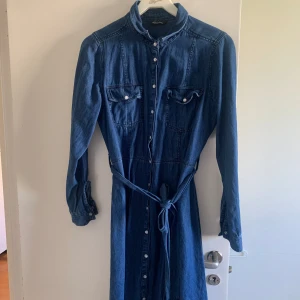 Jeansklänning - En långärmad och längre klänning med skärp och knappar hela vägen ner
