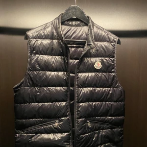 Moncler vest  - Svart moncler gui storlek 2 (s/m) Västen är givetvis äkta och köpt på wear the hype. Utöver det lilla hålet som på sista bilden är vesten i mycket gott skick. Priset kan diskuteras vid snabb affär och har du frågor är de bara att du hör av dig!