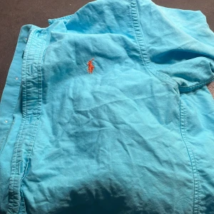 Polo raulph lauren skjorta - XL(18-20) Bra skick. Knappt använd. Turkos med orange Märke.