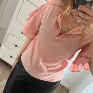 Rosa topp med dragkedja och volang  - Hej, jag säljer min fina rosa blus som har en dragkedja i mitten och volanger vid armarna. Toppen är i fint sick och sparsamt använd. Jättefin topp som funkar perfekt till flera olika tillfällen. Toppen är från Lindex barnavdelning. Storlek-S/M💕💕