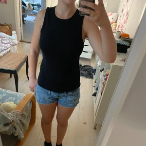 Svart ärmlös topp - En svart ärmlös topp i normal passform. Toppen har en rund halsringning och är tillverkad i ett stretchigt material.