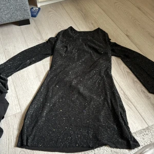 Klänning  - Svart glittrig klänning med öppen rygg! Köpte den på Merley för nåhot år sedan nypris 600, inga defekter och i nyskick 