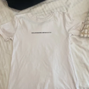Vit t-shirt från Pull&Bear - En vit t-shirt från Pull&Bear med texten 'SOCIAL DISTANCING WAS ALWAYS MY LIFESTYLE' tryckt på framsidan.💋😽💓
