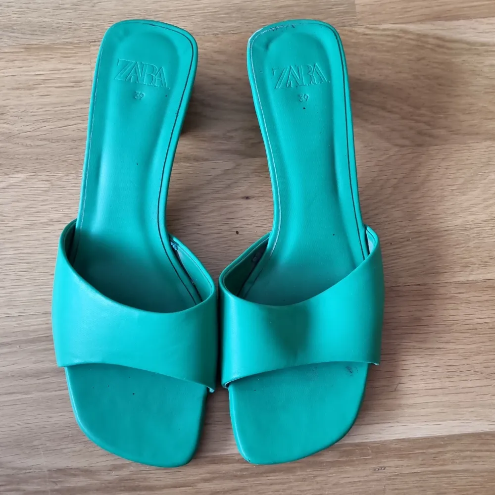 Ett par gröna sandaler från Zara med en bred rem över foten och en fyrkantig tå. Sandalerna har en låg klack och är i ett välanvänt skick.. Kengät.