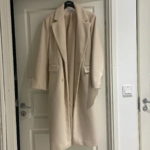 Beige kappa - Lång beige kappa från NA-KD. Säljer då det var en julklapp men inte riktigt min stil.  