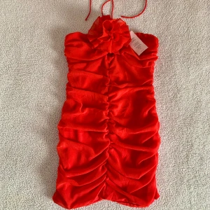 Nelly romantisk röd klänning med ros - Otroligt vacker klänning från Nelly i storlek 36. Knyta runt nacken. Perfekt klänning till alla hjärtans dag till exempel. Ny med tags kvar, utan anmärkningar. 🌹