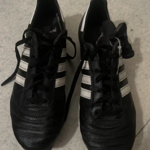 Adidas World cup SG fotbollsskor - Ett par svarta Adidas World cup SG fotbollsskor i storlek UK:9= EU:43. Inte i bästa skicket. Nya i denna storlek säljs för runt 1400kr
