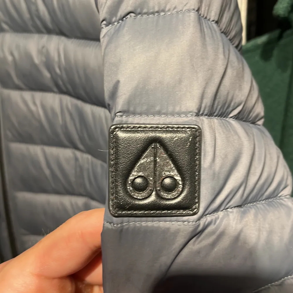 Tunnare dunjacka från Moose Knuckles Nypris 4300kr Två hål på höger ärm lagat med svarta lappar. Även en liten rosa fläck på baksidan därav priset.. Takit.