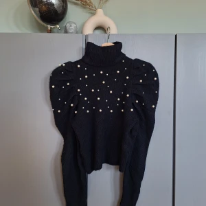 Gina tricot - svart stickad tröja med puffärm och pärlor strl XS  - Gina tricot - svart stickad tröja med puffärm och pärlor strl XS. Lite noppror men inget som stör, se bilder. Annars fin och sparsamt använd. Missa inte mina andra annonser 🩷🩷