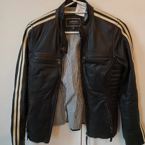 Marciano läderjacka - Äkta läderjacka i märket Marciano. Köpt på stadsmissionen för 1250kr. Fint skick. Randiga ärmar