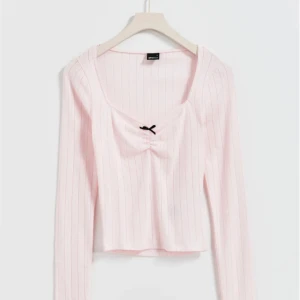 Ljusrosa topp med rosett - Tröjan har en söt ljusrosa färg och är pointellestickad med en rosett framtill. Den har en hjärtformad ringning, långa ärmar och en passform som kramar om midjan<3 Köpt från Gina Tricot för 259kr orginalpris. Använd max 5 ggr och har inga defekter💗💞 