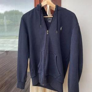 Säljer nu min Ralph lauren zip hoodie för den är för liten och säljer den för sjukt bra pris vill få den såld/ använd men använt den försiktigt. På andra bilden så har fixat ett litet håll som knappt syns/ skick 8/10. Skriv om ni har andra frågor👍 - Passar dem som är runt 175 är själv 178 och den är för liten!