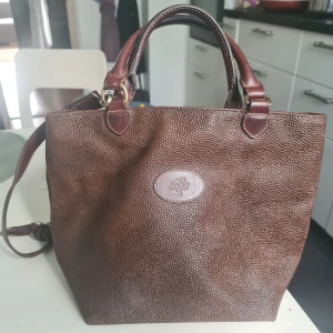 Äkta Burberry handväska  - Säljer fina handväska äkta Burberry. Köpt på NK i Stockholm. En innerficka. Rymlig trots det medelstora formatet. Äkta läder 