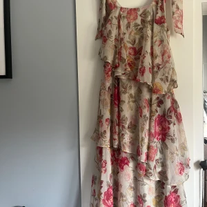 Maxi klänning blommor volanger - Maxi klänning med volanger. Banden går att knyta som mn vill