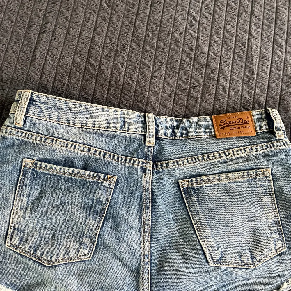 Ett par korta jeansshorts från Superdry. Snygg tvätt med snygga hål där fram. De är använda men i bra skick fortfarande 😉De är i storlek 26 och tyvärr för små för mig, de är anledningen till att jag säljer de. Skriv till mig om ni undrar nåt 🥰. Shorts.