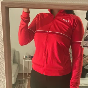 Nike träningsjacka - Röd träningsjacka från Nike. Oanvänd och prislapp kvar. Small men passar Medium. Köpt för 500kr och säljer för 350kr. Pris kan diskuteras.