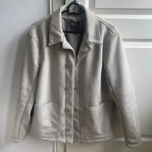 En grå/beige mocka jacka med knappar, knappt använd så den är helt hel och ren. 