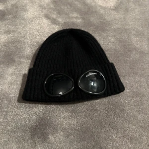 En cp company mössa som är en bra mössa till vintern. Mössan är ej äkta! - Skicket på denna mössa är väldigt knappt använd!