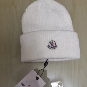 Moncler mössa  - Hej  Säljer en moncler mössa då jag känner att mössor passar inte mig. Mössan är helt ny och oanvänd   Har en till mössa exakt likadan i svart om man skulle välja ha den istället, den är med helt ny och oanvänd!