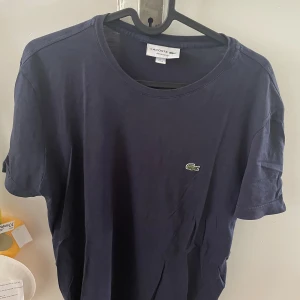 T-shirt: Lacoste - Sparsamt använd i gott skick. Storlek M. Säljes i samband med för liten storlek.   Pris: 200kr