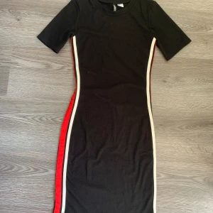 Klänning - Bodycon klänning som aldrig använts, den har röd och vit sträck på båda sidorna. 